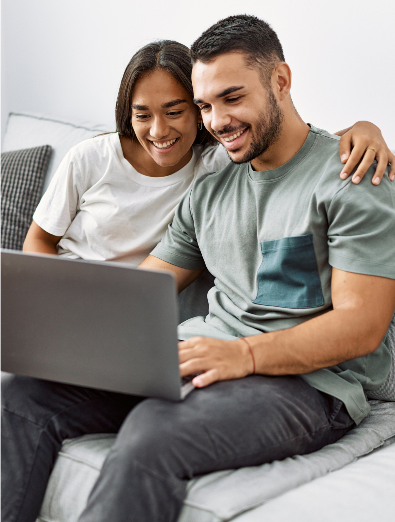 a man and woman sitting on a couch looking at a laptop.