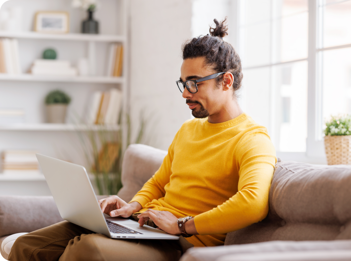 a man sitting on a couch using a laptop.