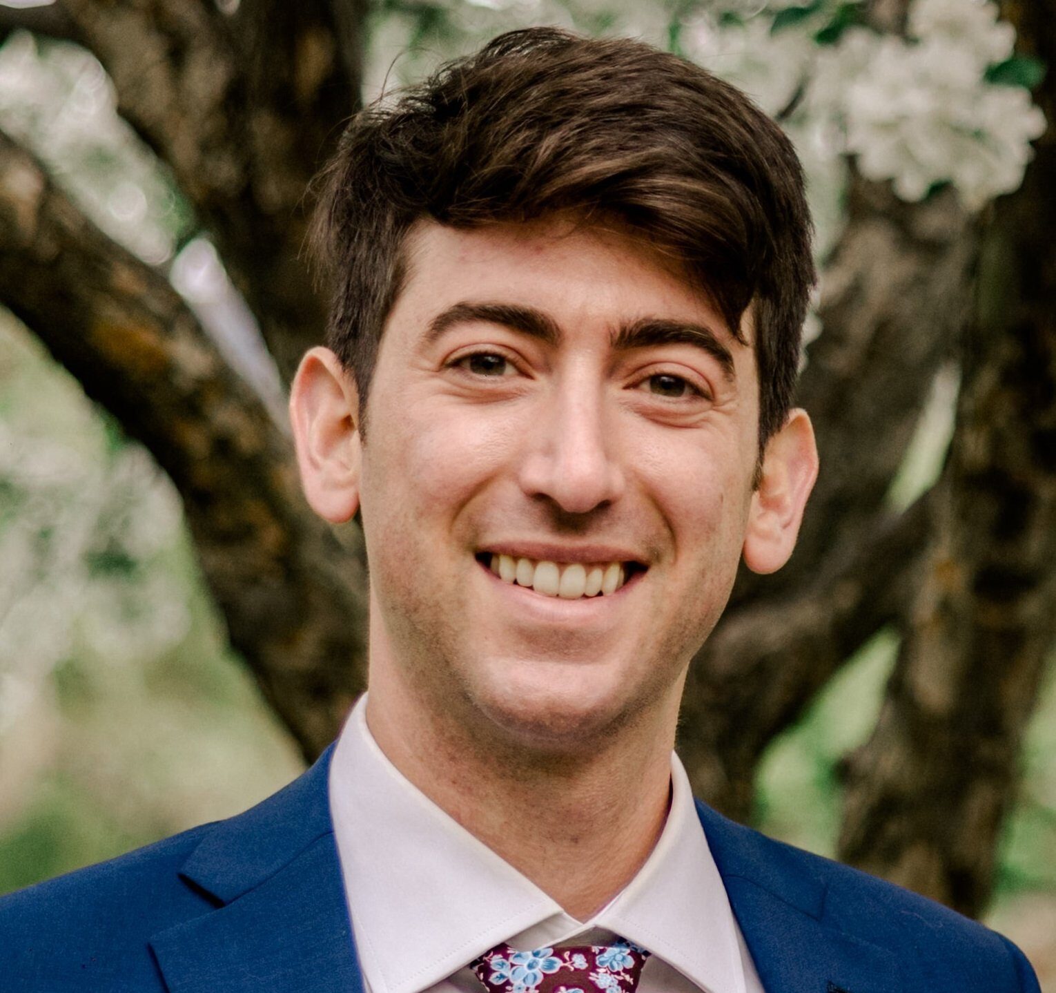 a man in a suit and tie smiling at the camera.