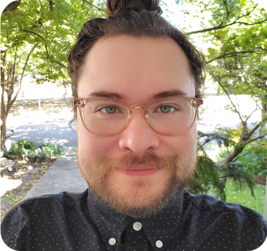 a man with glasses and a beard wearing a polka dot shirt.